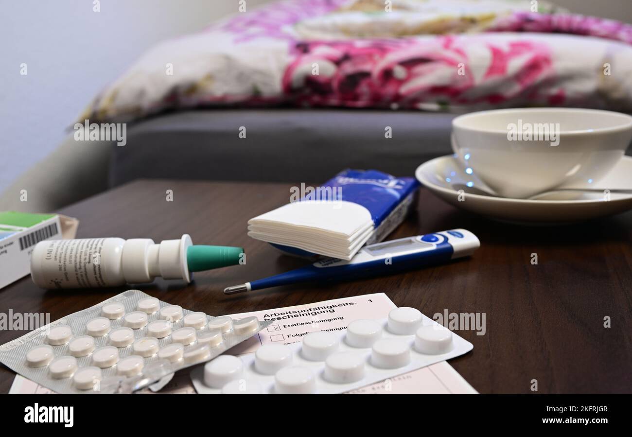 Stuttgart, Allemagne. 18th novembre 2022. Un thermomètre de fièvre, un médicament et un certificat d'incapacité de travail du médecin (note de maladie) sont posés sur une table de chevet (scène posée). Avec la saison froide, les infections de la grippe sont à nouveau en hausse. Credit: Bernd Weißbrod/dpa/Alay Live News Banque D'Images