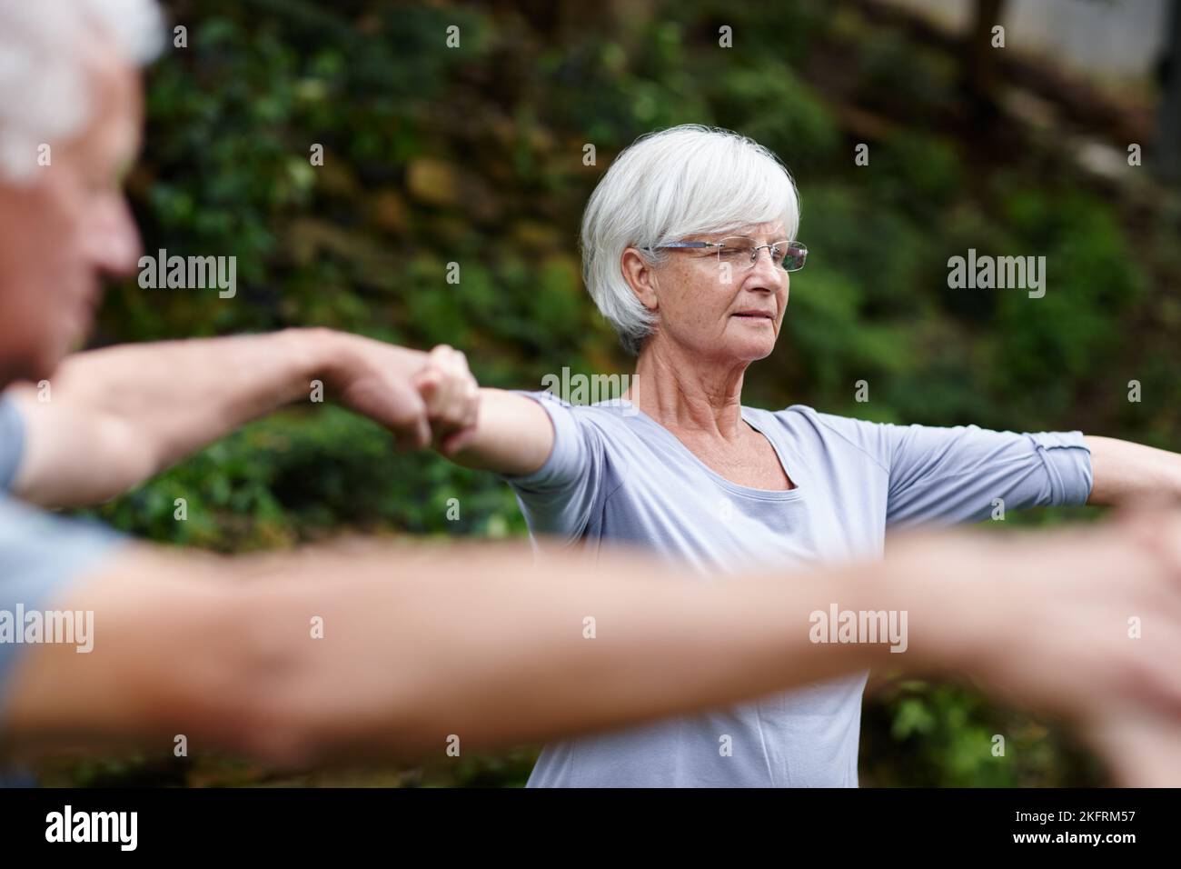 Pratiquer la pleine conscience. Une femme âgée tenant les mains avec les gens se fait du yoga avec. Banque D'Images