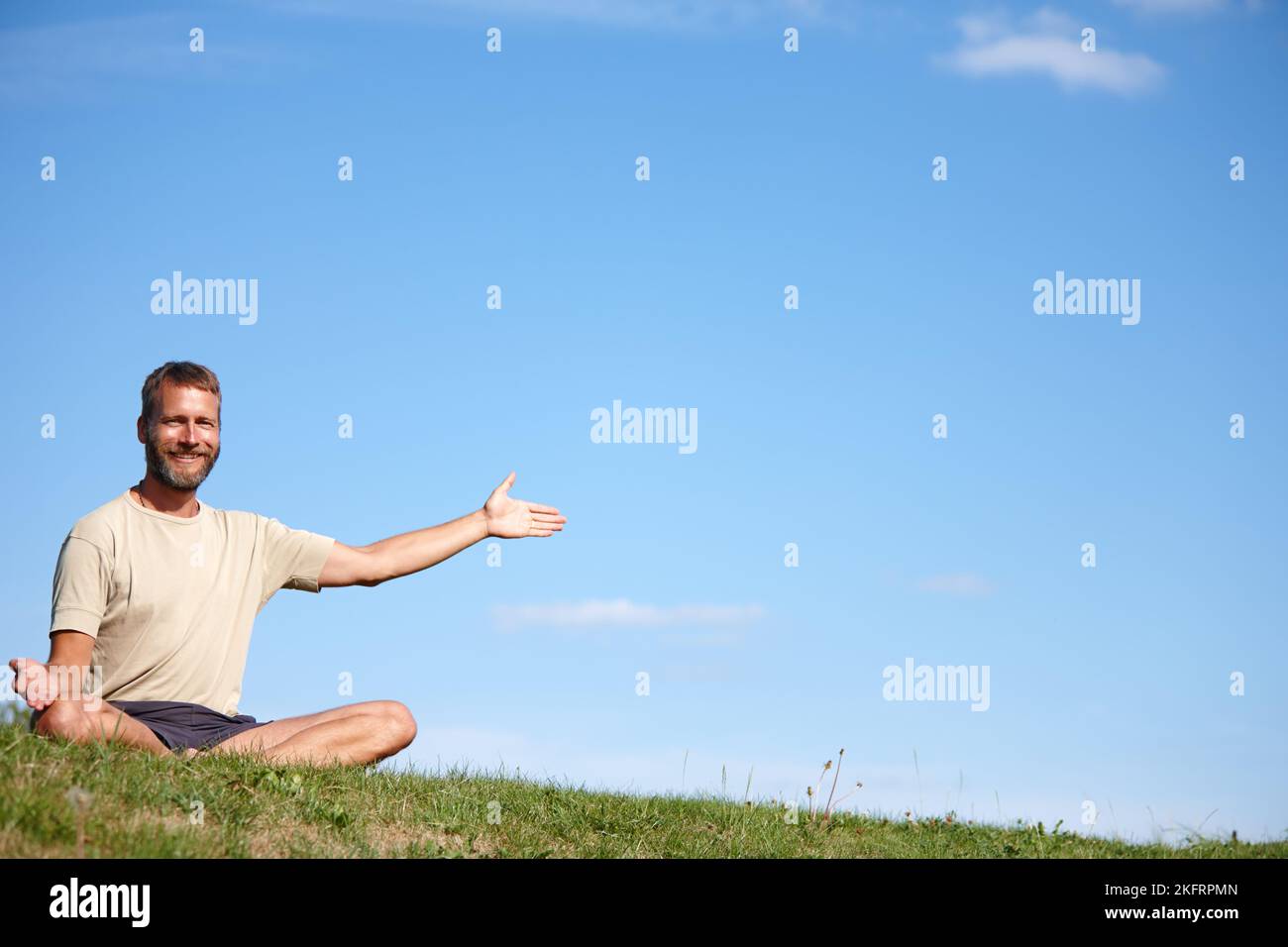 Vous montrant certains de ses secrets de bien-être. Portrait d'un beau homme mature présentant copyspace tout en étant assis dans la position de lotus à l'extérieur. Banque D'Images