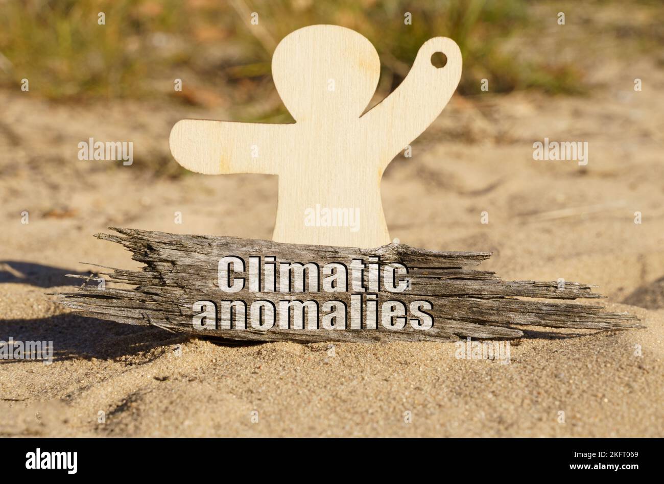 Écologie. Sur le sable près de la figurine en bois d'un homme il y a un morceau de bois avec l'inscription - anomalies climatiques Banque D'Images