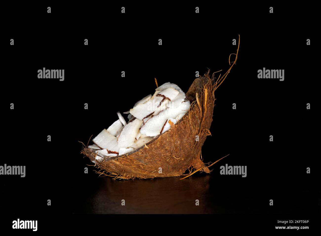 Viande de noix de coco finement tranchée dans une coquille de noix de coco, photographie de nourriture avec fond noir Banque D'Images