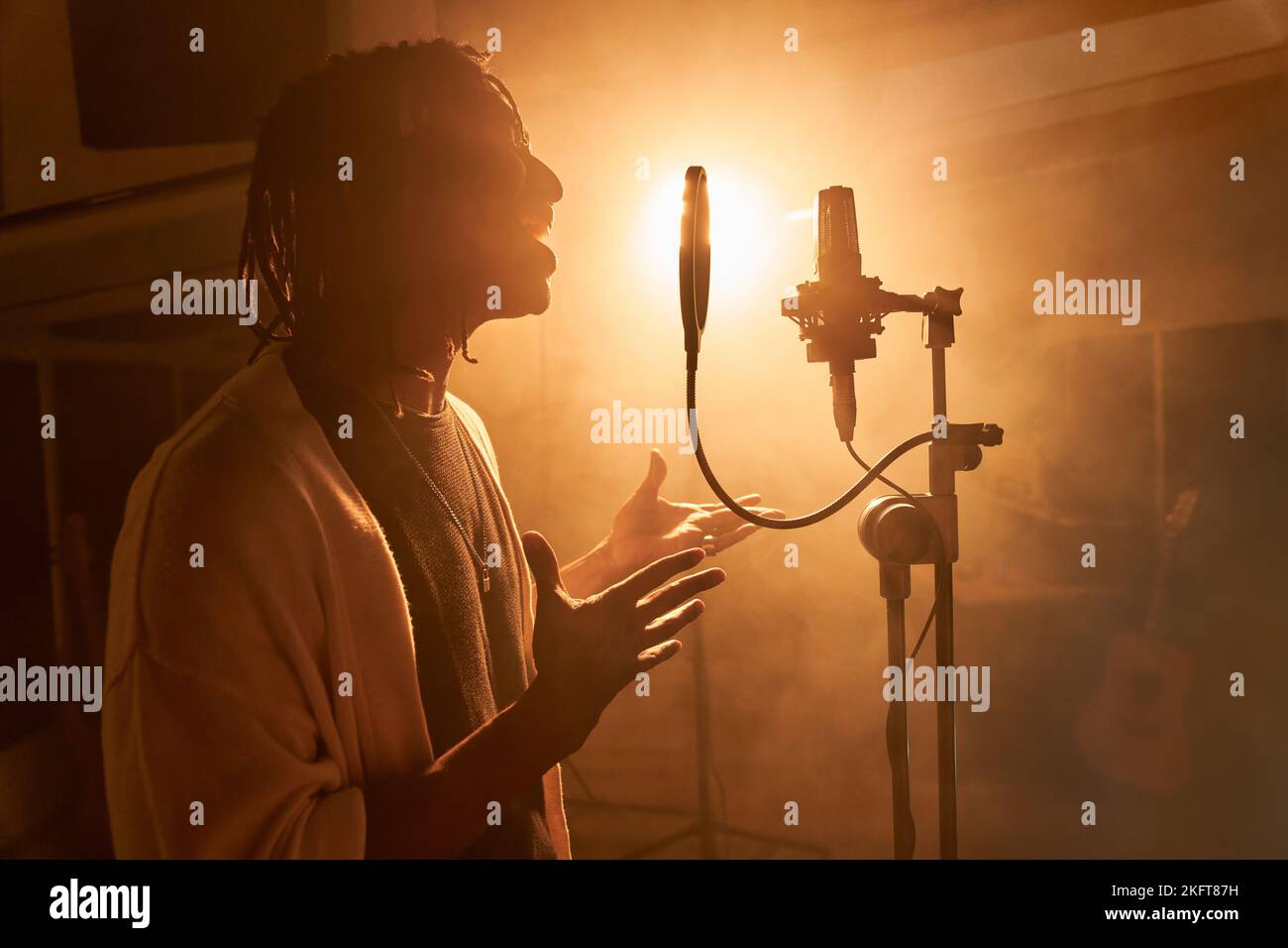 Vue latérale du chant masculin afro-américain sur le microphone en position rétro-éclairée Banque D'Images