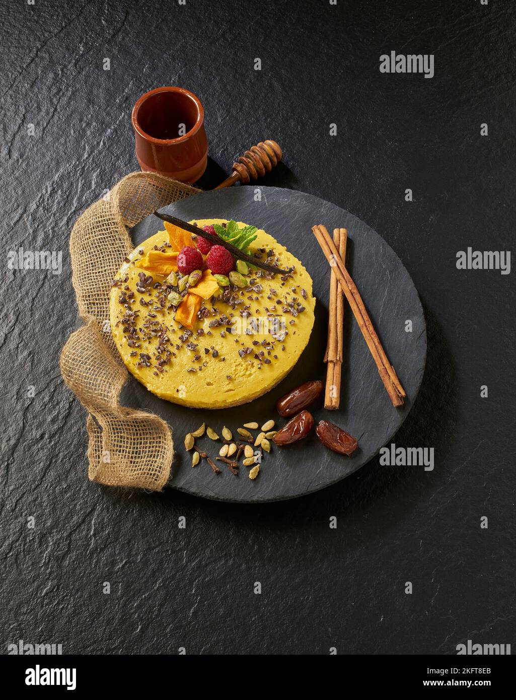 De dessus de savoureux gâteau jaune décoré avec des framboises et gousse de vanille près du miel de balancier sur la serviette Banque D'Images