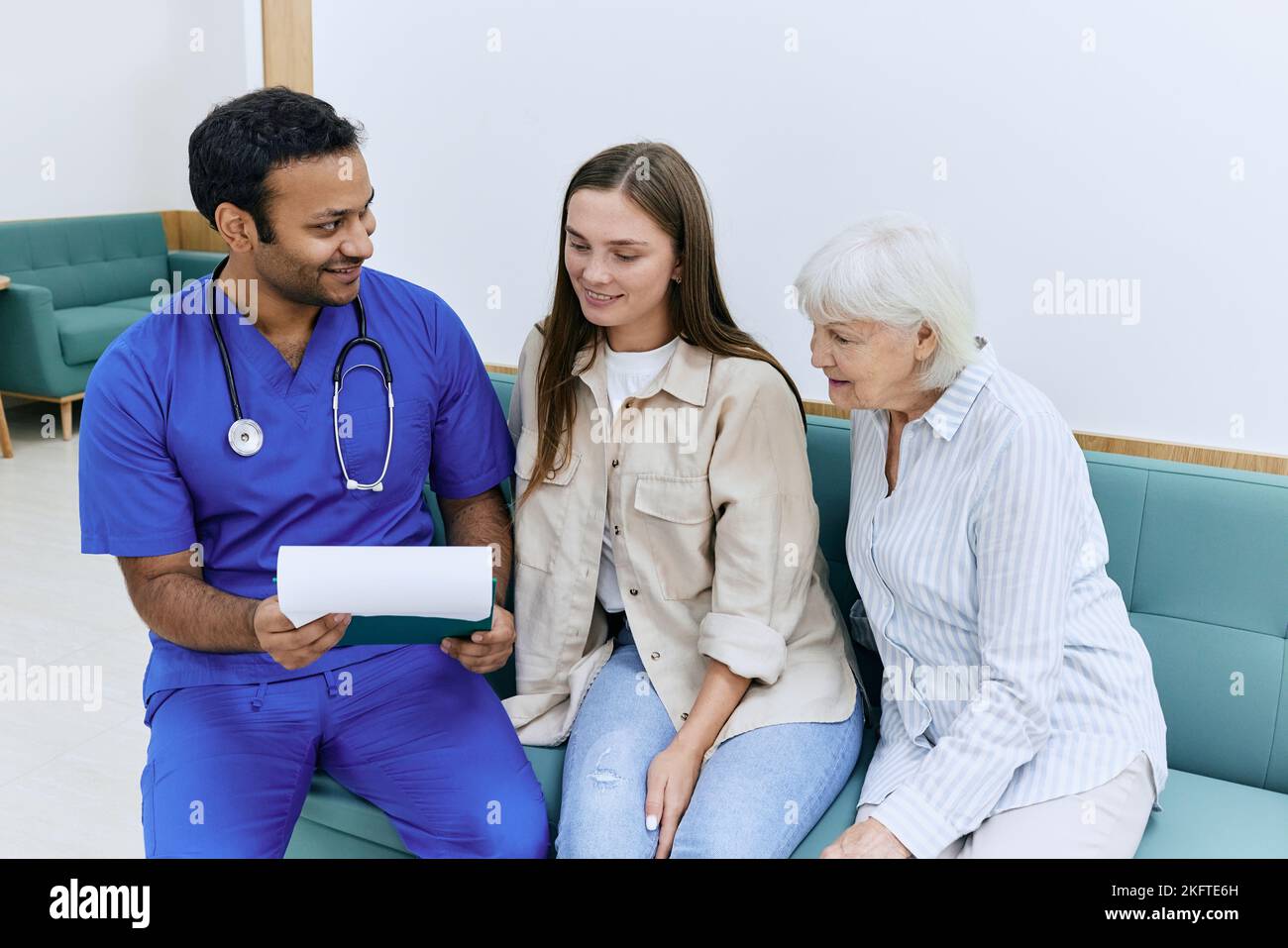 médecin racontant aux patientes âgées de bonnes nouvelles sur sa santé après le traitement à l'hôpital tout en étant assis sur le canapé dans le couloir de l'établissement médical wit Banque D'Images