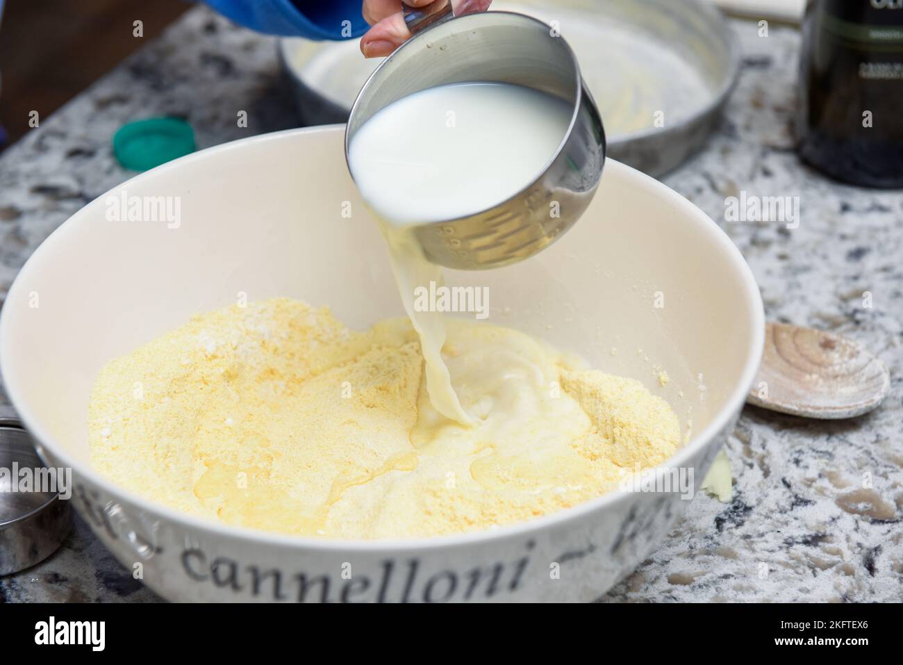 Cuire du pain à la maison en versant du lait dans le mélange de farine Banque D'Images