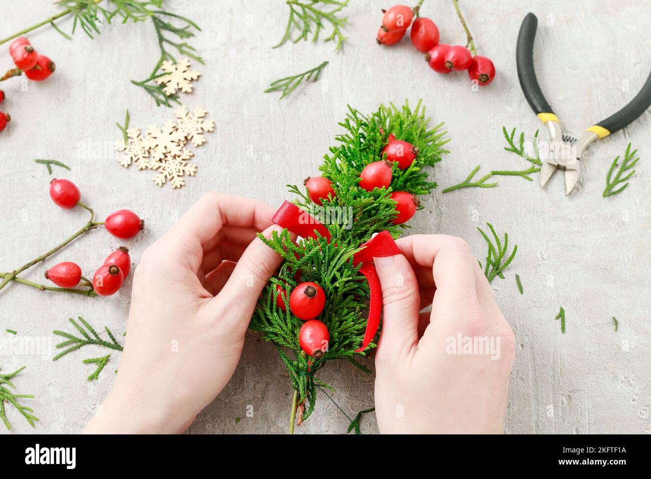 Un fleuriste au travail : Comment faire de noël traditionnelle couronne de porte avec thuja brindilles et Wild Rose fruits. Pas à pas, tutoriel. Banque D'Images