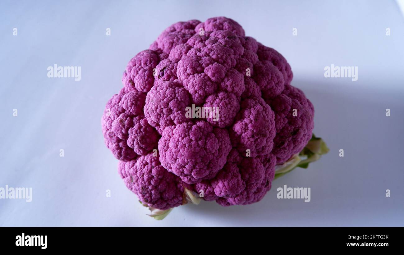 Vue frontale de chou-fleur violet ou violet entier sur le plancher blanc, isolé. Banque D'Images