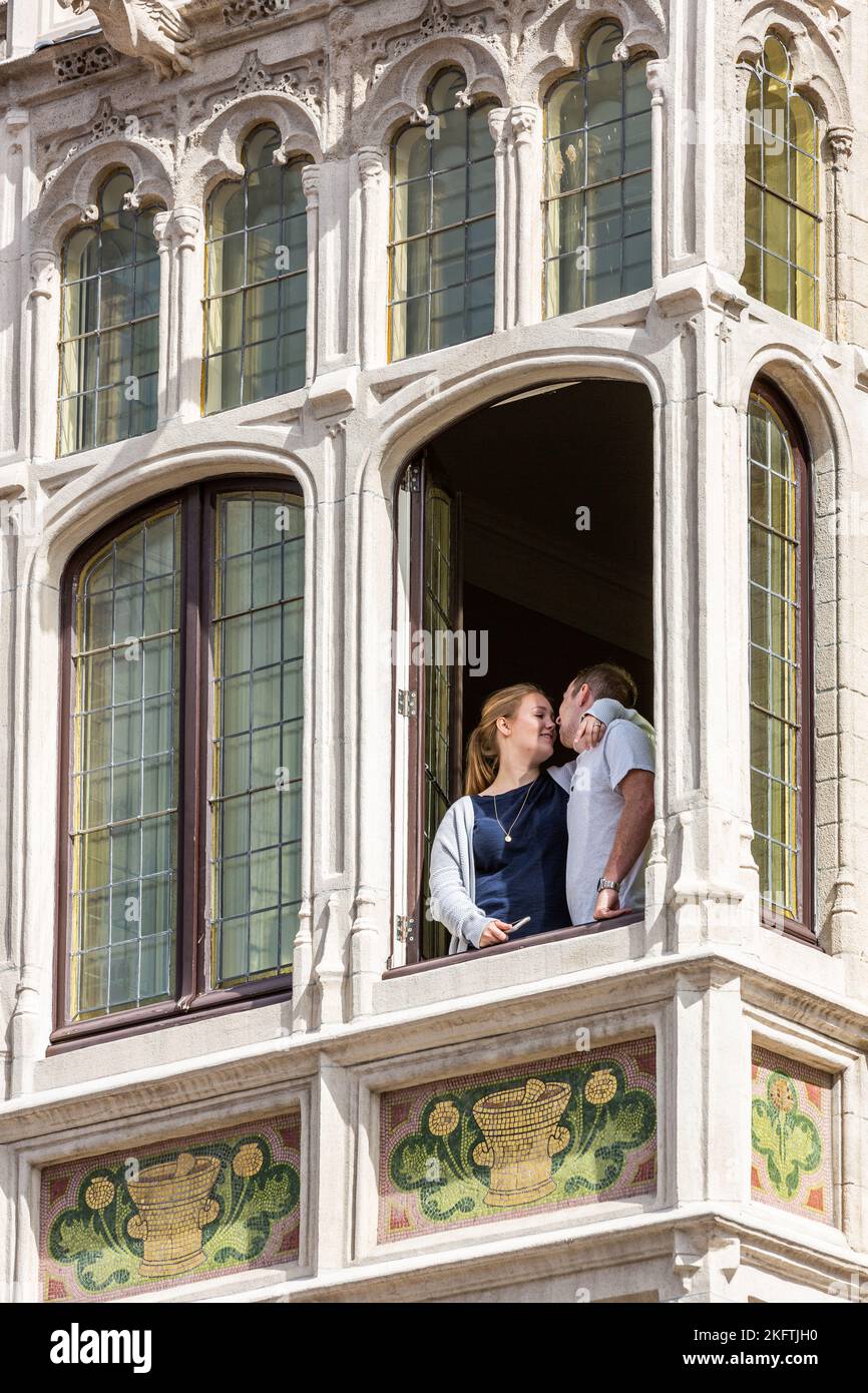 Couple embrassant à la fenêtre d'un vieux bâtiment à Bruxelles, appelé la pharmacie anglaise. Banque D'Images