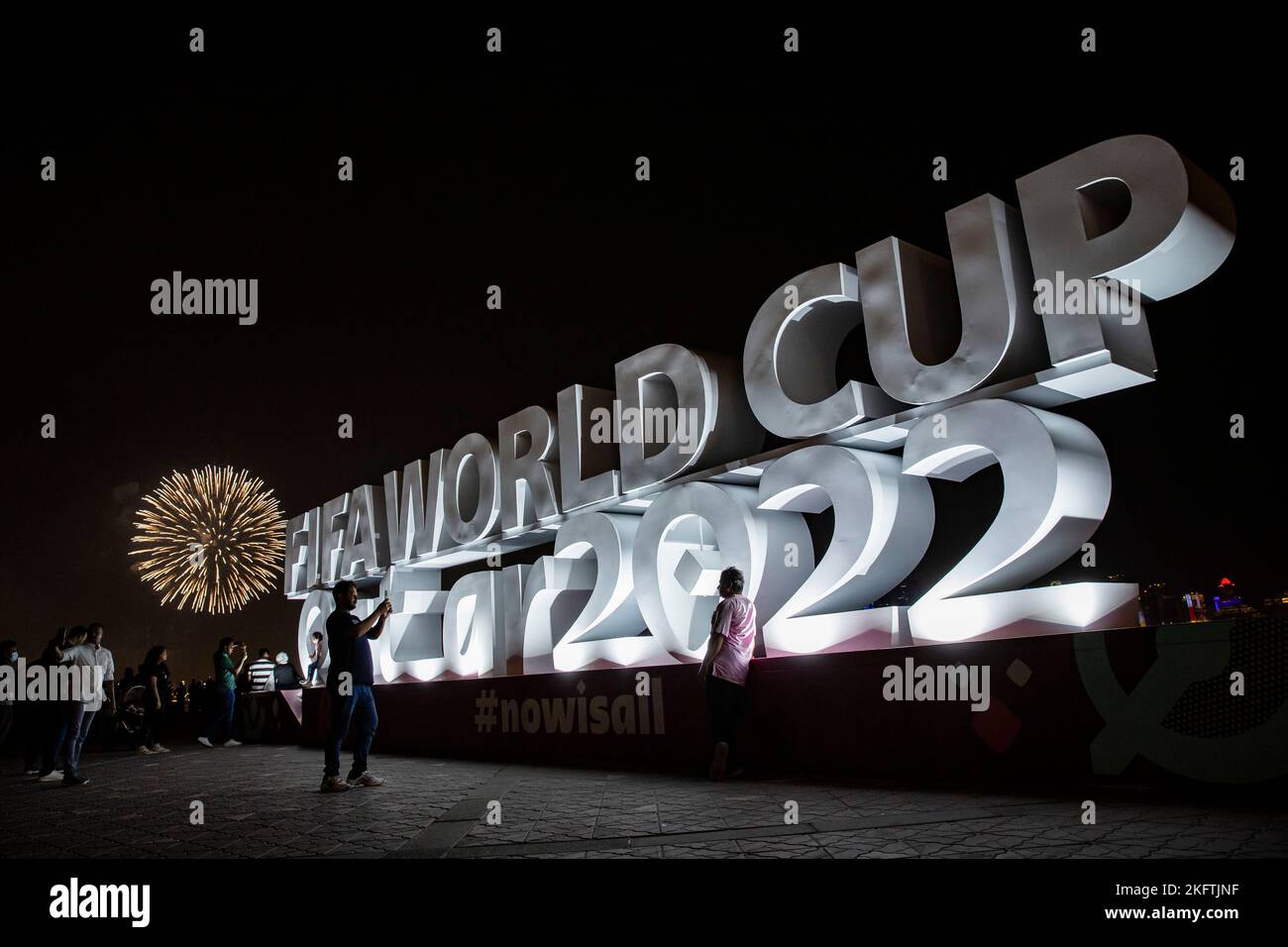 Doha, Qatar. 19th novembre 2022. Football, préparation de la coupe du monde au Qatar, deux personnes prennent une photo devant le lettrage 'coupe du monde de la Fifa Qatar 2022'. Les feux d'artifice sont visibles en arrière-plan. Crédit : Tom Weller/dpa/Alay Live News Banque D'Images