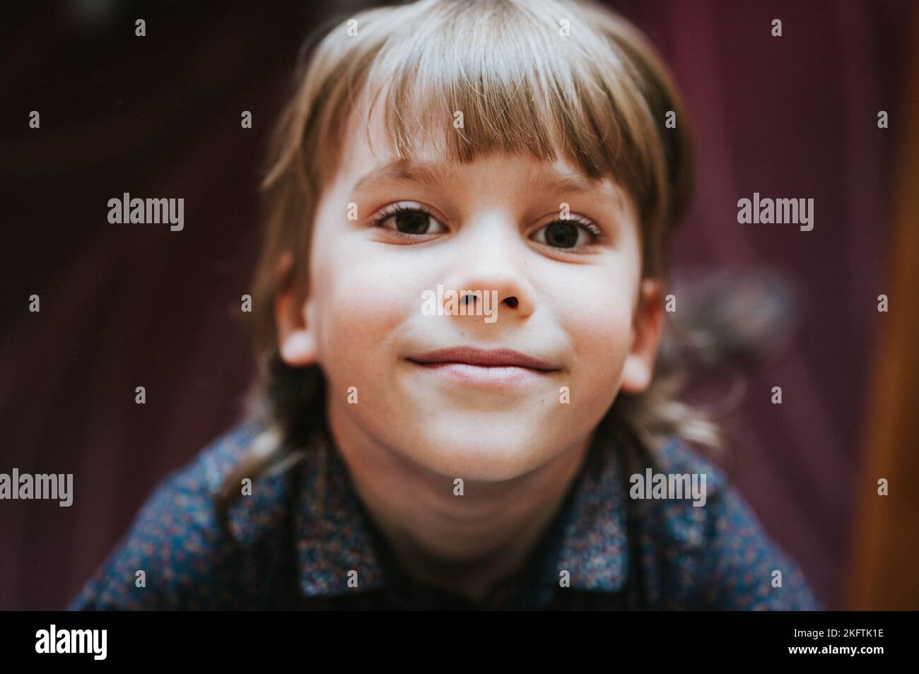 portrait du visage de mignon heureux souriant boueux petit garçon de six ans cheveux blonds de garçon regardant l'appareil photo à la maison style de vie Banque D'Images