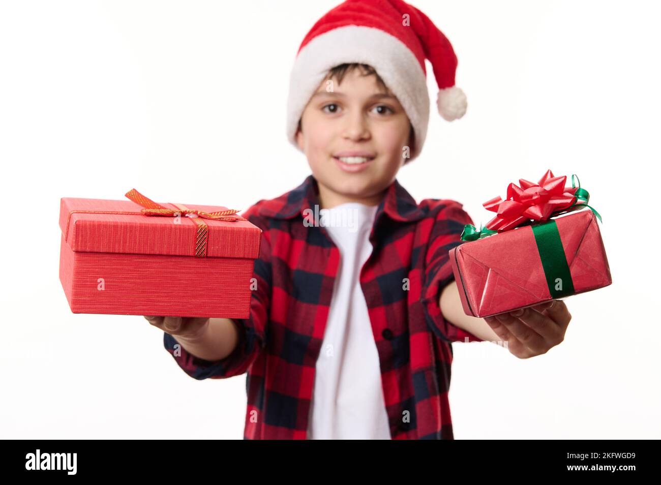 Concentrez-vous sur les cadeaux de Noël ou du nouvel an entre les mains d'un joli petit garçon en chapeau de père Noël, isolé sur fond blanc Banque D'Images