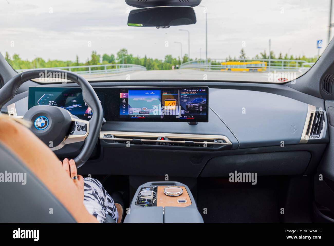 Vue rapprochée des mains féminines sur le volant de la BMW IX40 de voiture électrique pendant la conduite. Banque D'Images