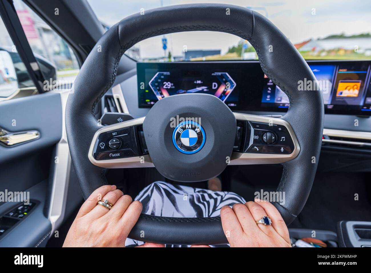 Vue rapprochée des mains féminines sur le volant de la BMW IX40 de voiture électrique pendant la conduite. Suède. Banque D'Images