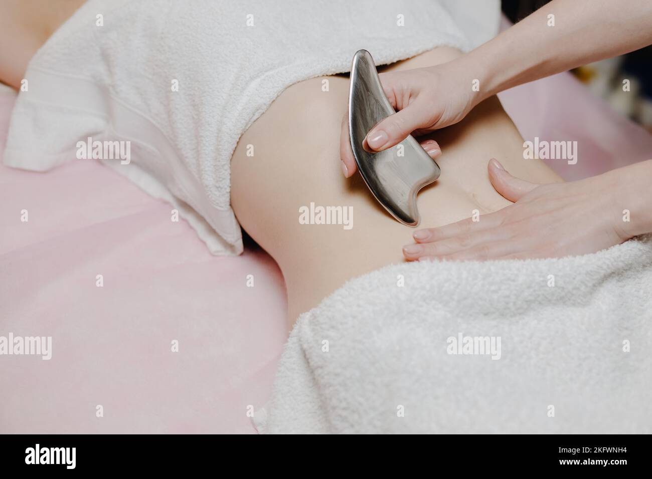 Massage avec une palette de massage spéciale, pétrissage des points de déclenchement dans l'abdomen, gros plan. Massage des lames. Vue latérale. Placer pour le texte Banque D'Images