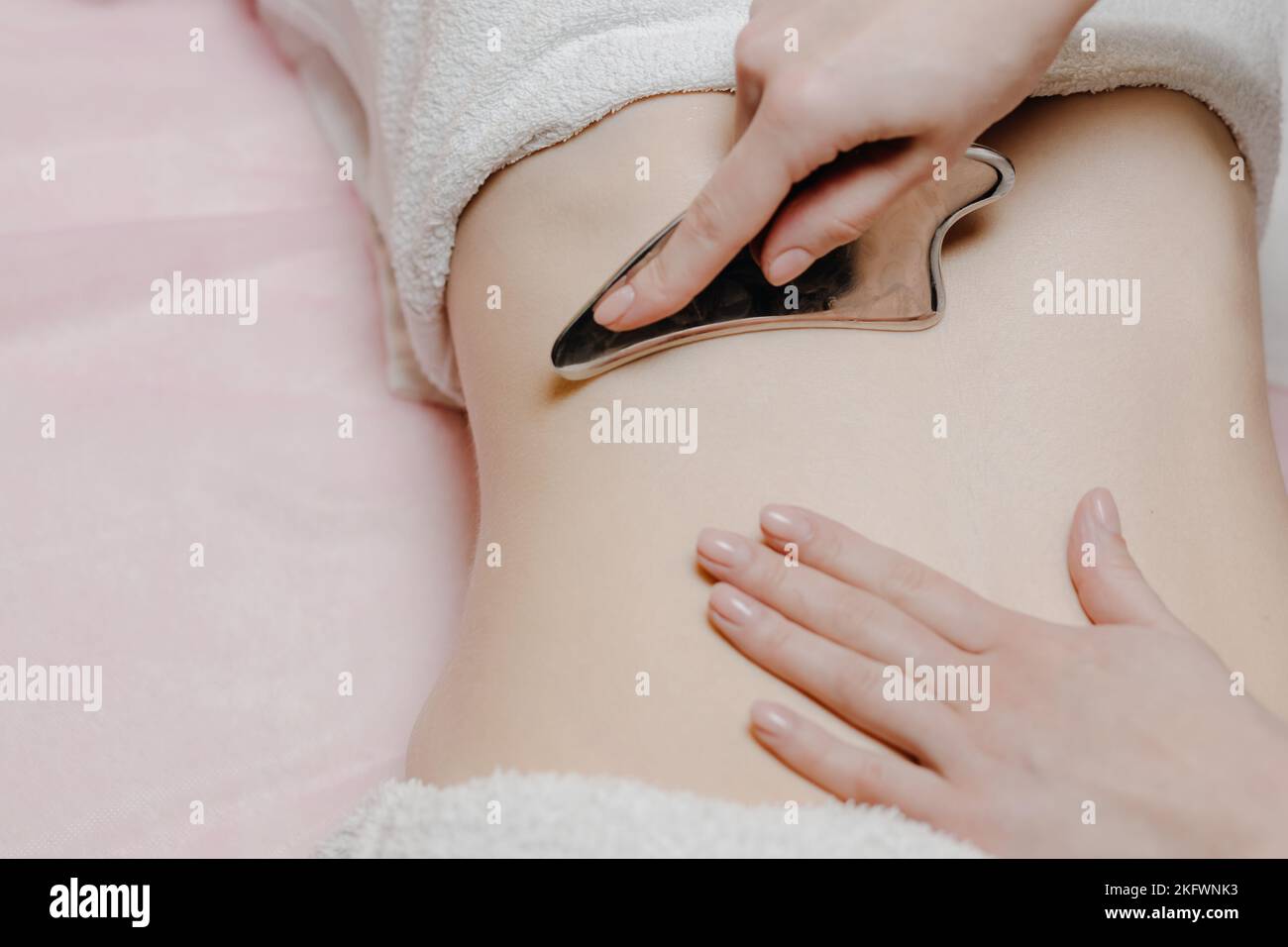 Massage avec une palette de massage spéciale, pétrissage des points de déclenchement dans l'abdomen, gros plan. Massage des lames. Vue de dessus Banque D'Images