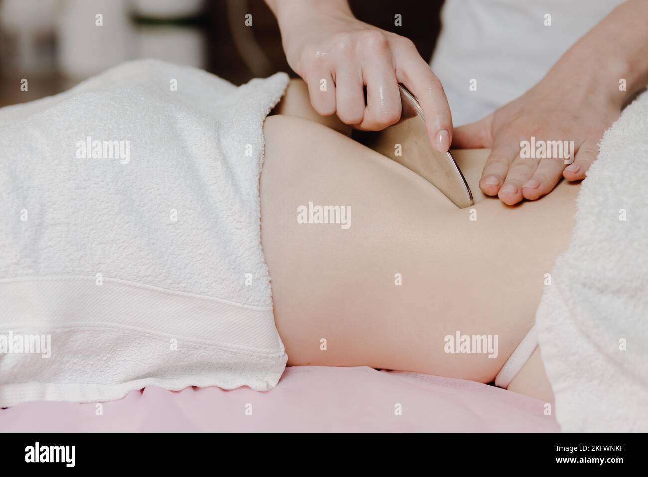 Massage avec une palette de massage spéciale, pétrissage des points de déclenchement dans l'abdomen, gros plan. Massage des lames. Vue latérale Banque D'Images