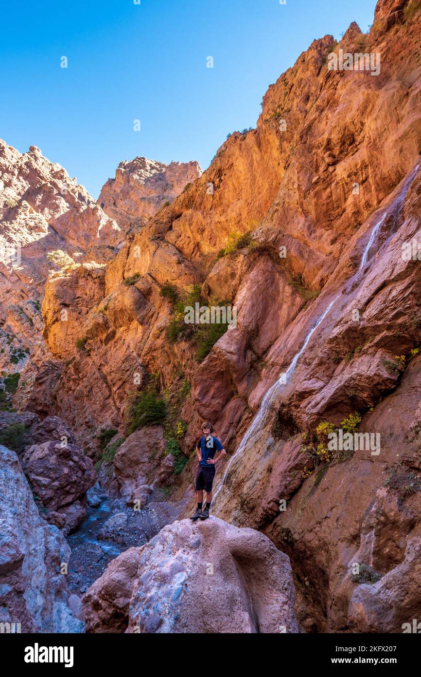 Trekker mâle dans une gorge étroite du massif m'Goun des montagnes de l'Atlas marocain Banque D'Images