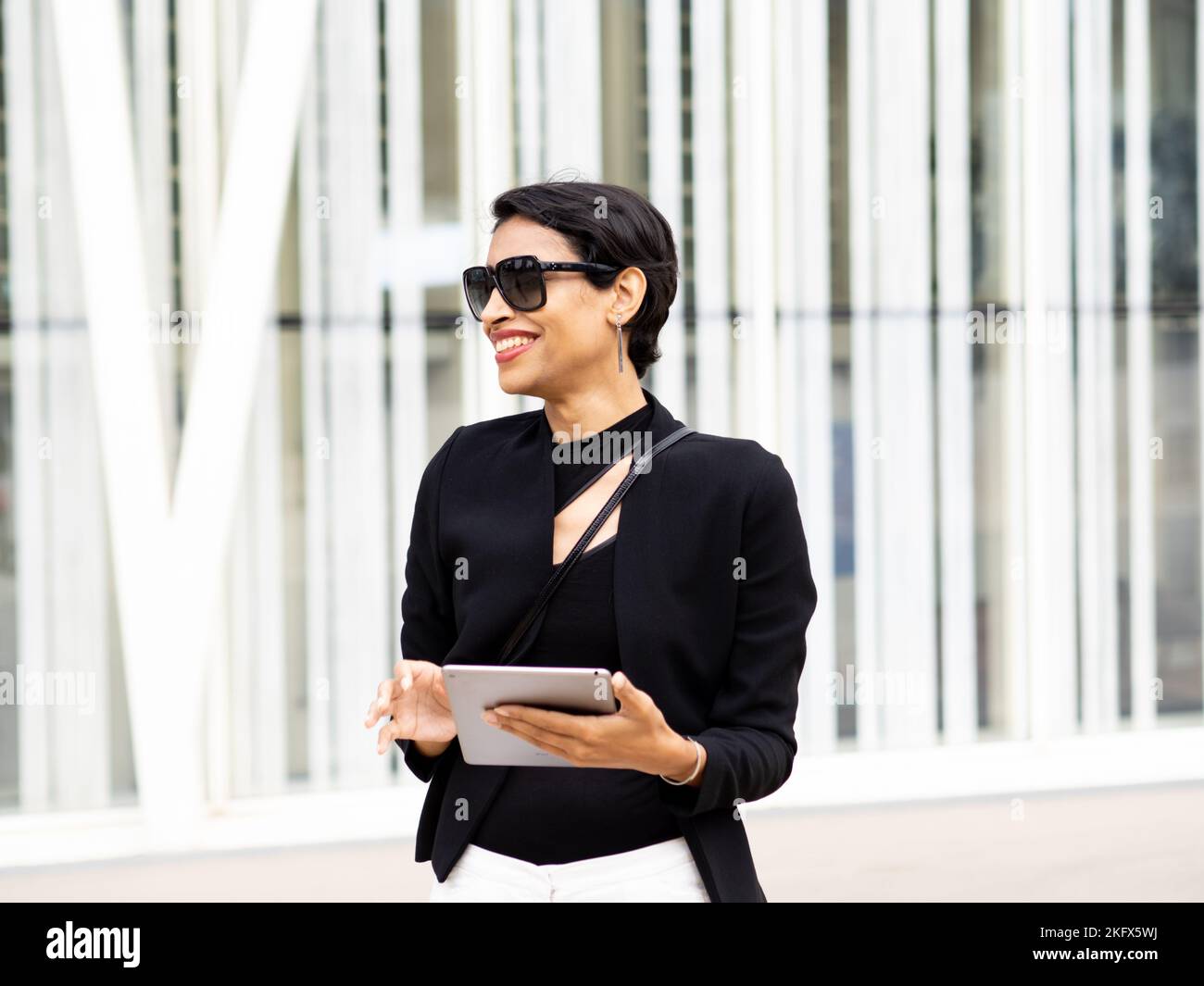 Femme d'affaires souriante et transgenre utilisant une tablette dans un quartier d'affaires Banque D'Images