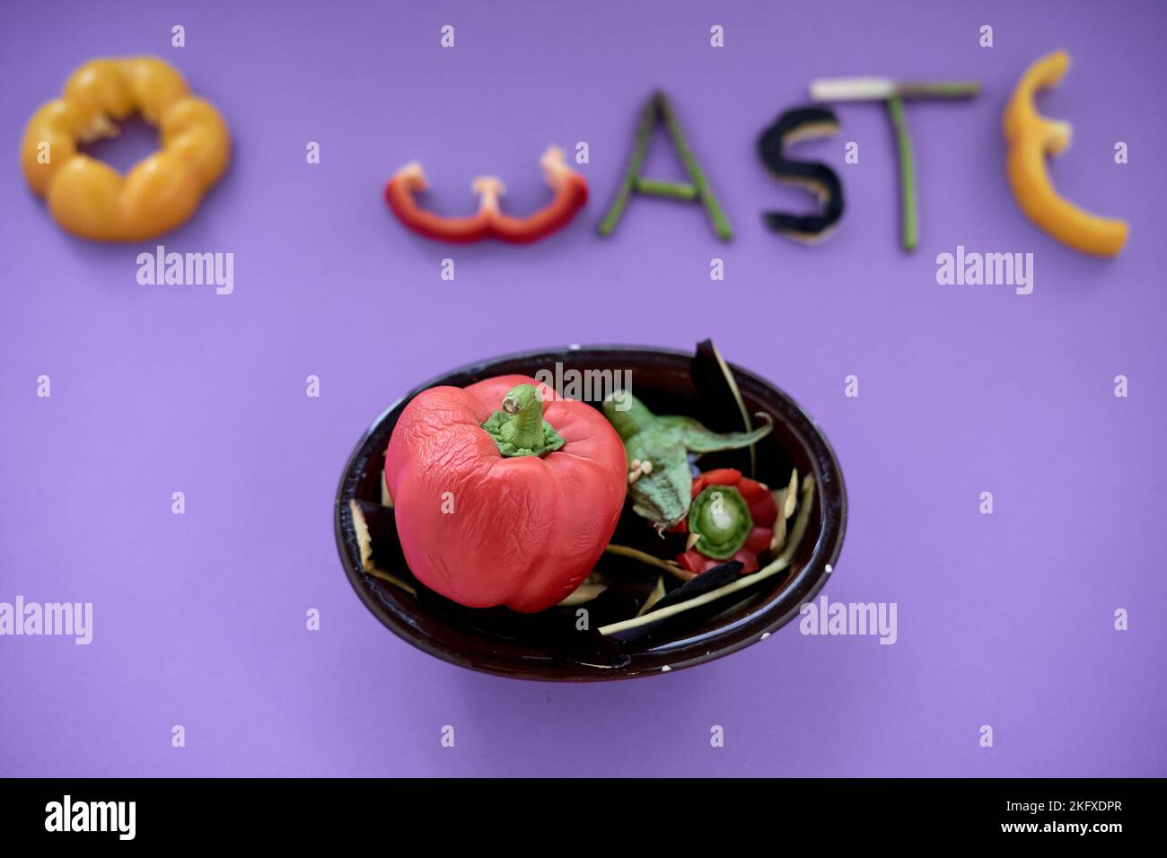 morceaux de légumes comestibles formant le mot zéro déchet à côté d'un bol noir avec des poivrons Banque D'Images