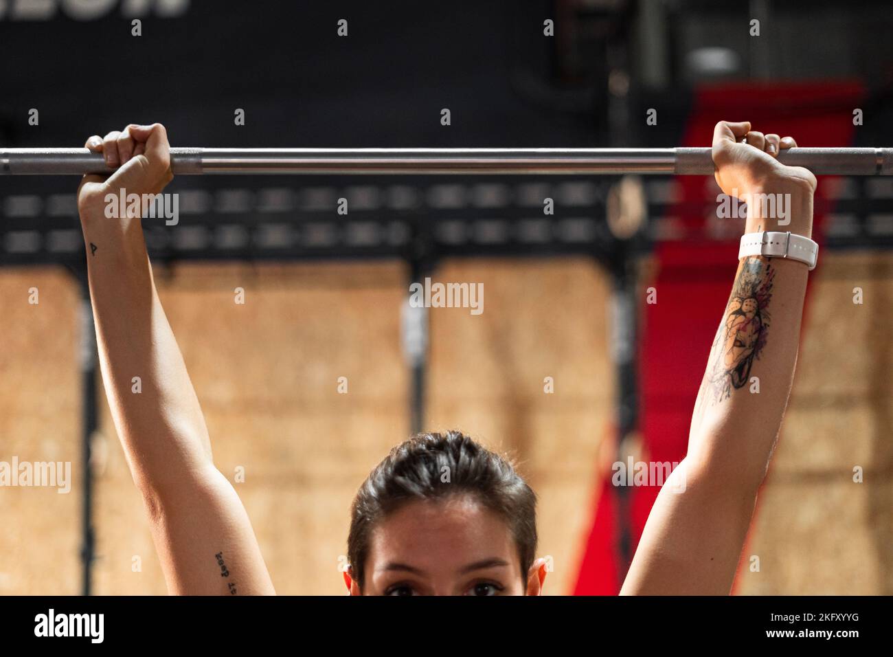 gros plan mains de brunette caucasienne fille avec tatouages tenant la barre d'haltérophilie dans une salle de gym Banque D'Images