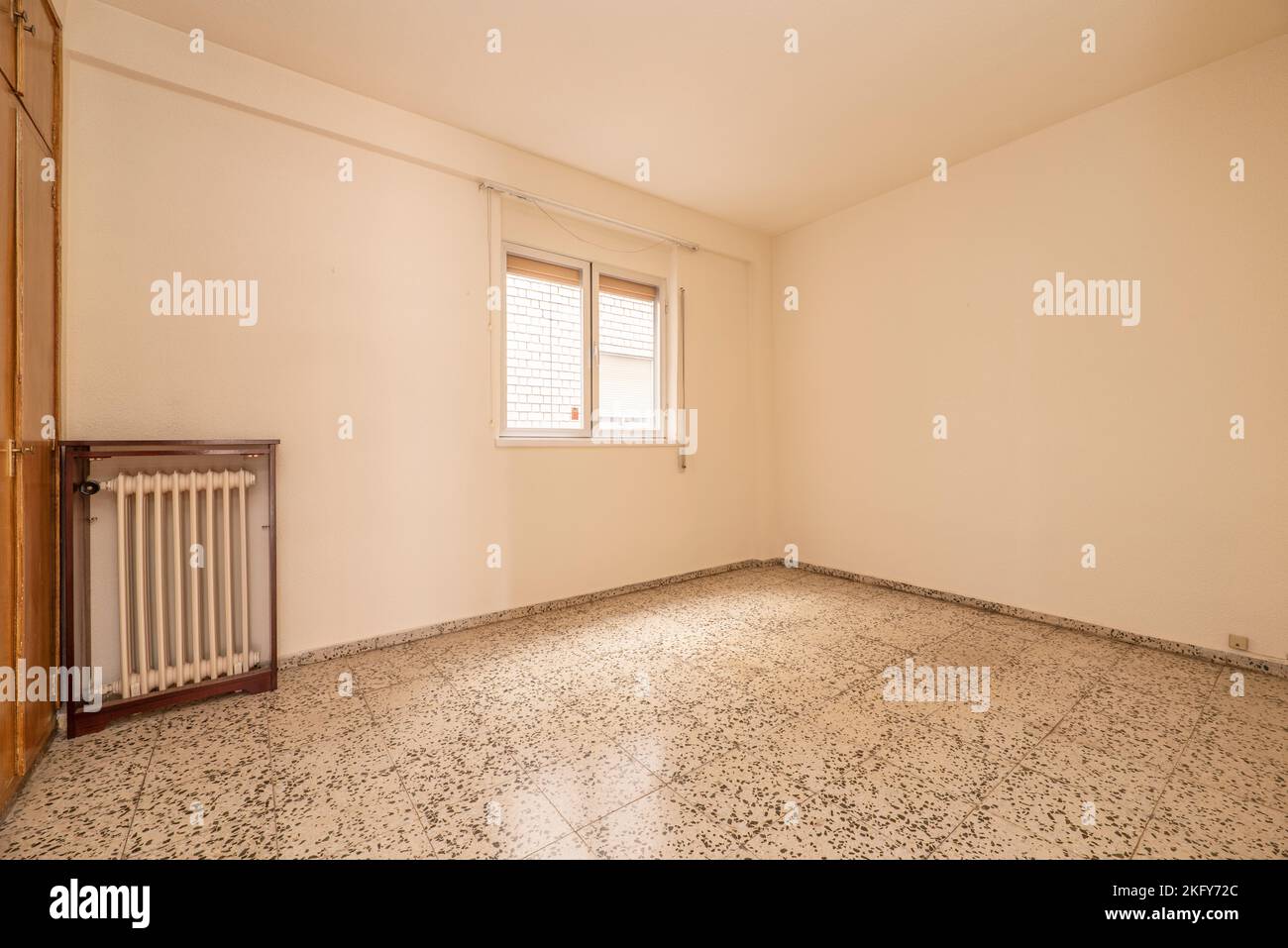 Cette chambre vide dispose d''une armoire intégrée, d''un radiateur en fer forgé blanc et de fenêtres en aluminium avec des volets Banque D'Images