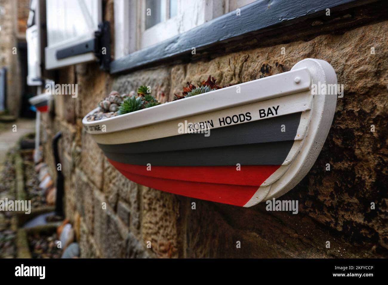 Jardinière en forme de bateau de sauvetage sur un mur de chalet à Robin Hoods Bay, North Yorkshire, Royaume-Uni Banque D'Images