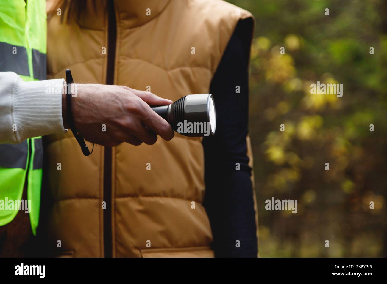 Équipe de recherche et de sauvetage de bénévoles avec une lampe de poche en forêt, gros plan sur la lampe de poche à portée de main Banque D'Images