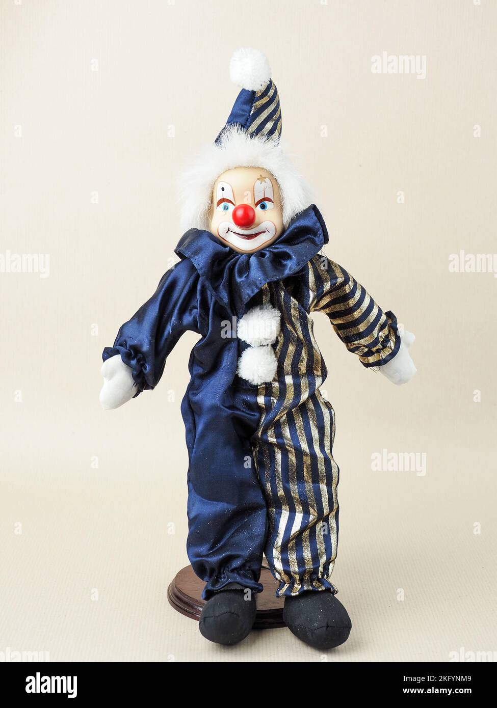 Dans cette illustration, un clown blanc vintage avec poupée nez rouge dans un costume bleu avec chapeau. Des poupées en porcelaine sont apparues au 18th siècle en France. Ils ont été utilisés pour promouvoir la mode française dans le monde. Habituellement, de telles poupées étaient fournies avec un grand nombre de vêtements et envoyées aux clients sous forme de mini mannequins. Banque D'Images