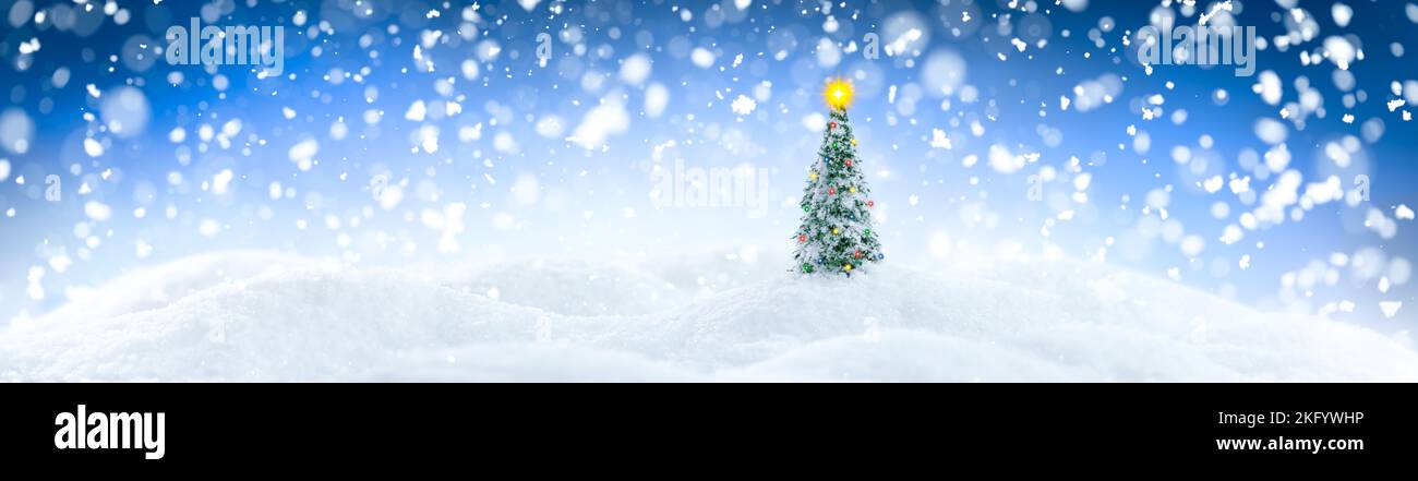 Paysage hivernal avec un seul arbre de Noël sur des perdrides de neige blanches étincelantes entourées de chutes de neige Banque D'Images