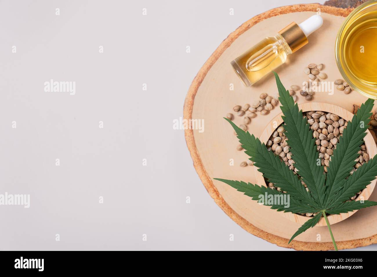 Le lot de marijuana légalisée comprend une feuille de chanvre vert, de l'huile de CBD dans une bouteille avec un couvercle compte-gouttes et un bol en verre, et des graines de chanvre exposées sur un bois Banque D'Images