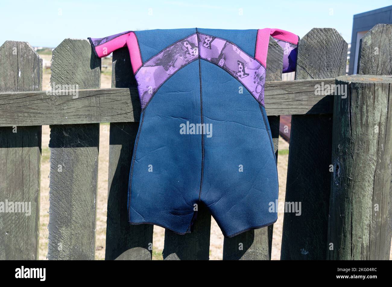 Une combinaison moulante bleue, pourpre et rose a été accrochée au-dessus d'une clôture jusqu'à jour après avoir été utilisée. Banque D'Images