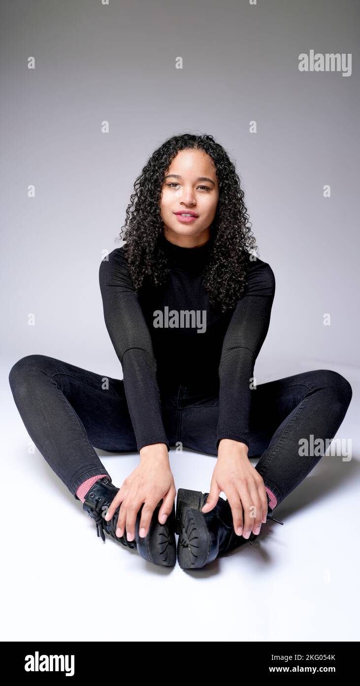 Jeune femme multiraciale assise dans les Cobblers pose sourire | fond blanc avec espace de copie Banque D'Images