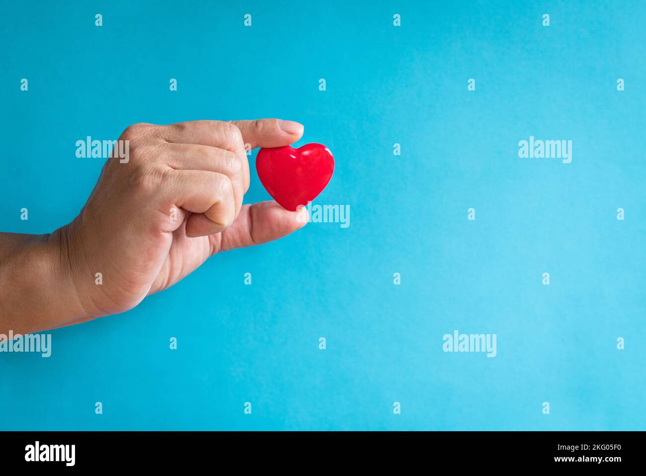 Concept de santé cardiaque. Le doigt de l'homme tenant une forme de coeur rouge. Copier l'espace. Banque D'Images