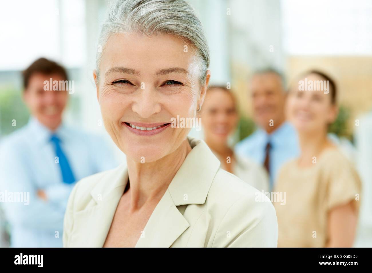 Cadre supérieur souriant avec succès et équipe à l'arrière. Portrait en gros plan d'une femme d'affaires senior qui a réussi en souriant avec ses collègues Banque D'Images