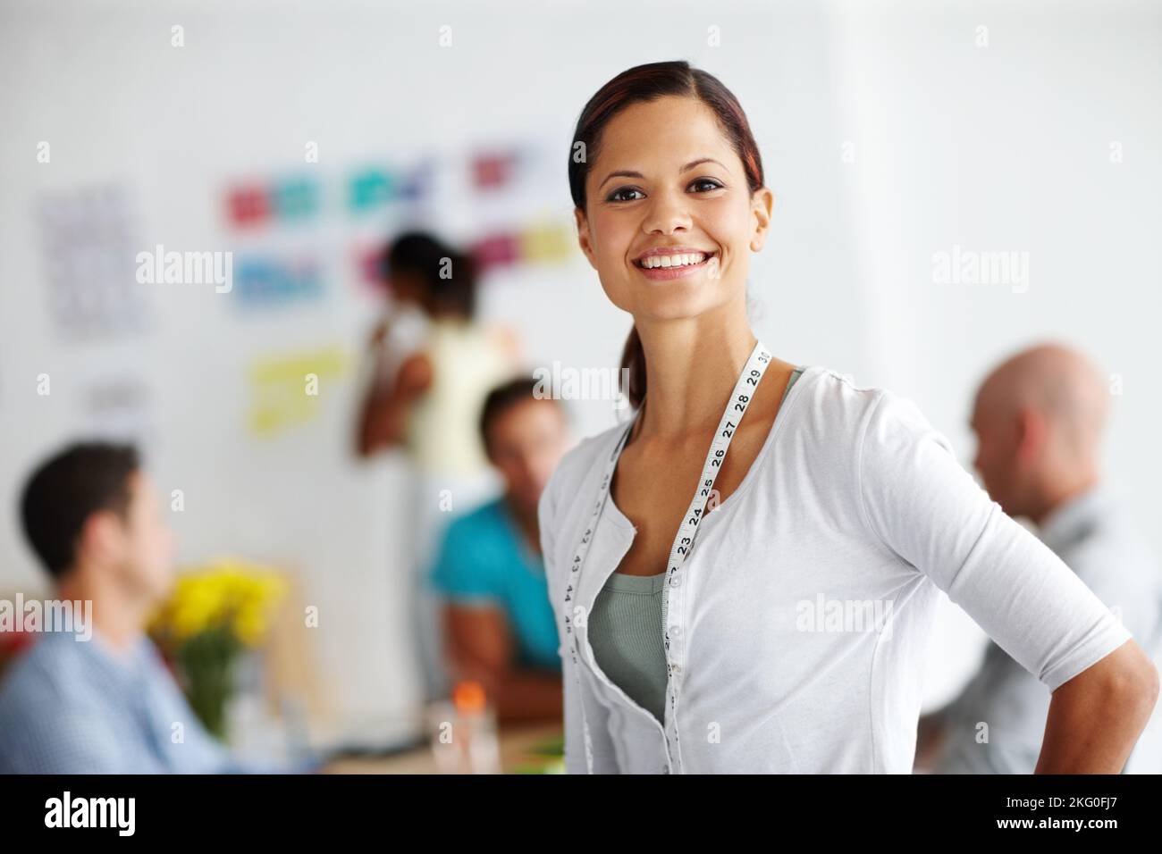 Ils utilisent des technologies anciennes et nouvelles dans leurs conceptions. Portrait d'une jeune femme qui a l'air confiante avec un mètre ruban autour de son cou et de ses collègues Banque D'Images