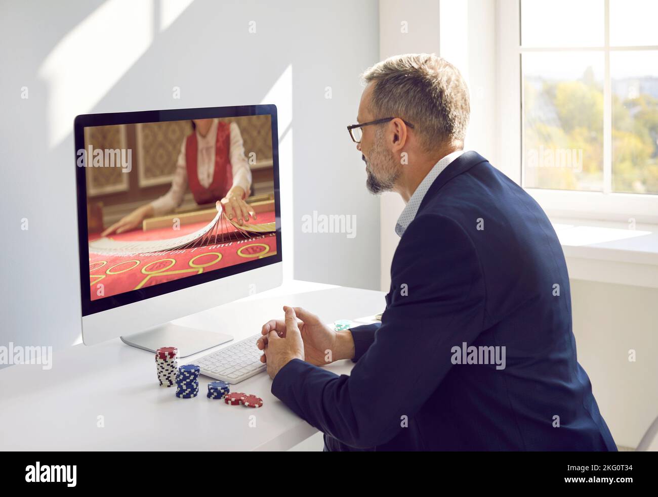 Un homme d'affaires concentré joue au poker en ligne tout en étant assis à l'ordinateur au bureau. Banque D'Images