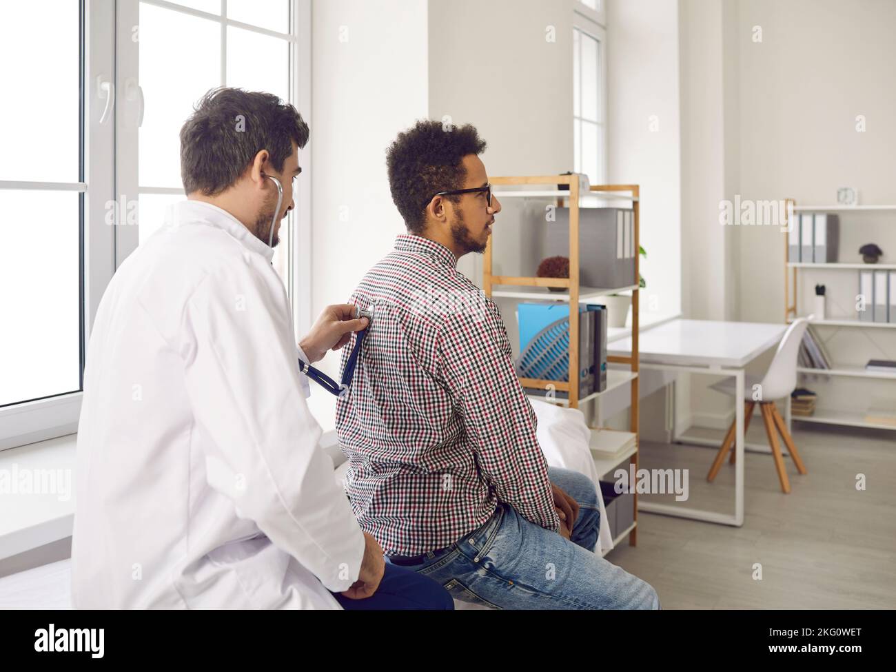 Pendant le rendez-vous médical, le médecin écoute les poumons du patient avec un stéthoscope pour la respiration sifflante. Banque D'Images