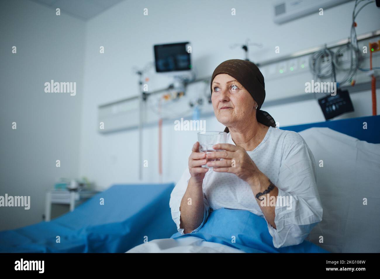 Femme âgée assise dans la chambre d'hôpital après une chimiothérapie. Banque D'Images