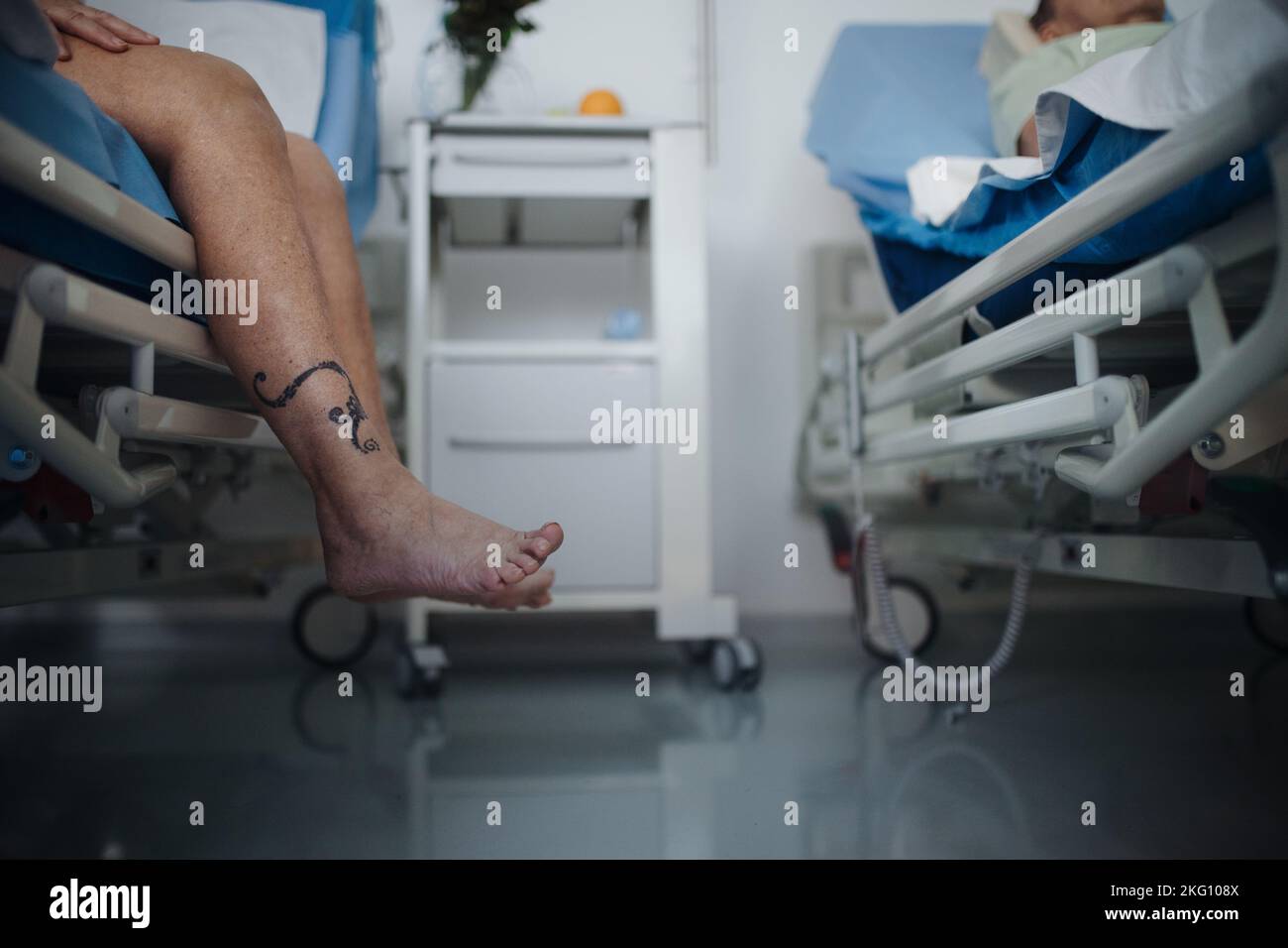 Gros plan de la jambe des femmes essayant de sortir du lit d'hôpital. Banque D'Images