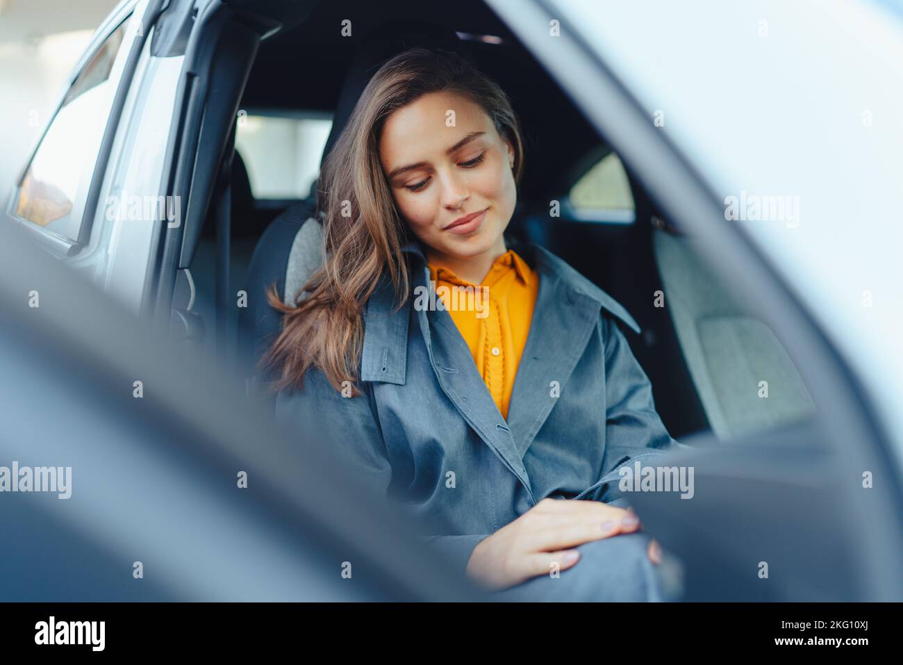 Une jeune femme excitée assise dans sa voiture, attendant quelqu'un. Banque D'Images