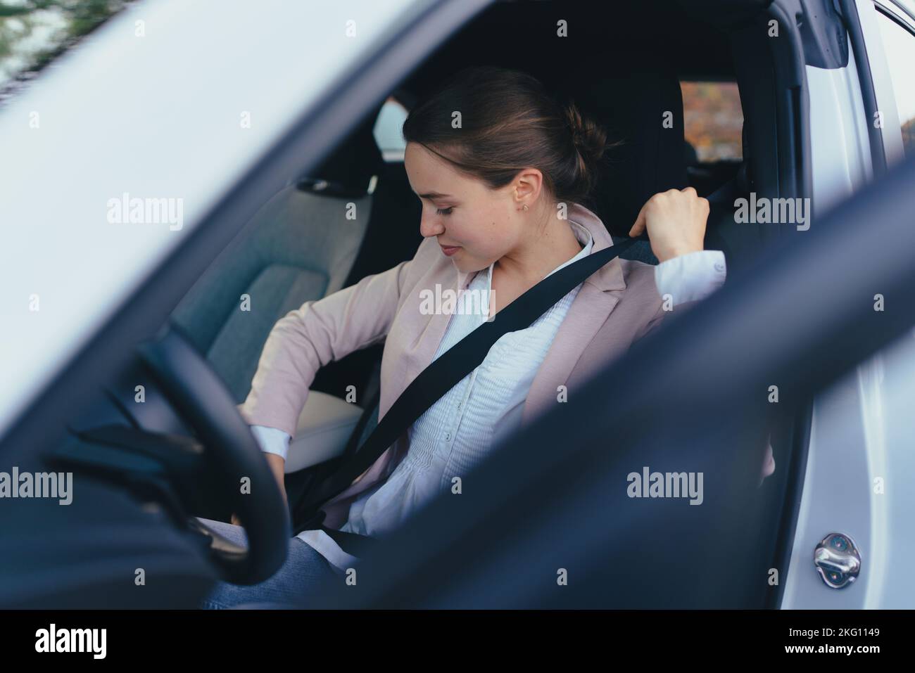 Jeune femme donnant la ceinture de sécurité en voiture, se préparant à une conduite, concept de conduite de sécurité. Banque D'Images