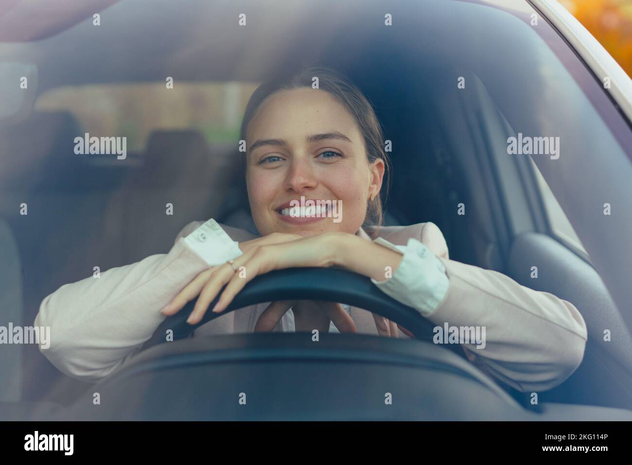 Une jeune femme excitée assise dans sa voiture, prête à conduire. Banque D'Images