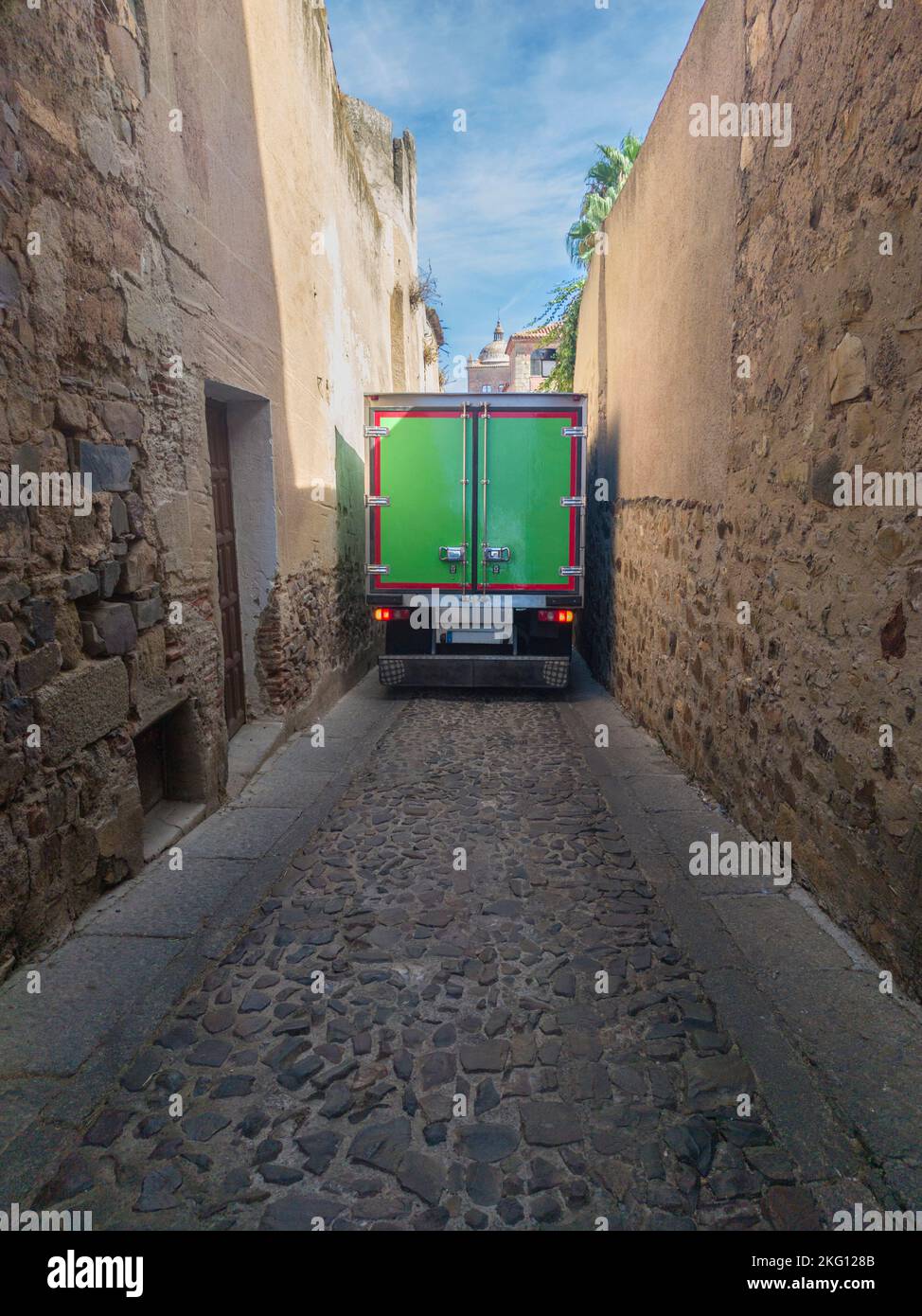 Camion semi-remorque roulant prudemment à travers une rue étroite au centre-ville. Livraison à la vieille ville concept Banque D'Images