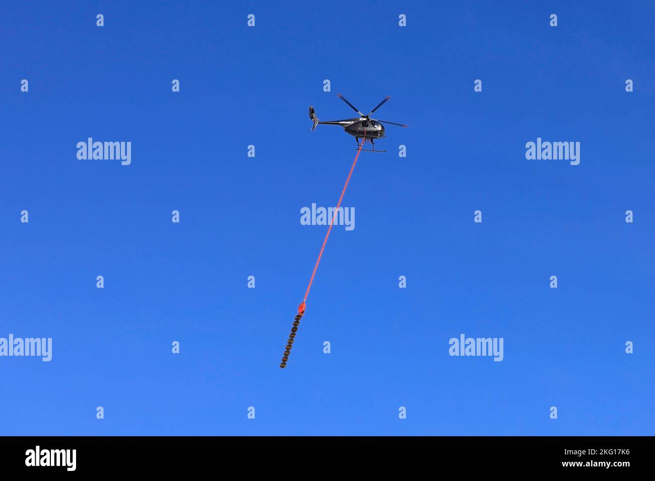 Hélicoptère Heliwest et scie aérienne pour couper les arbres par des lignes électriques contre le ciel bleu. Copier l'espace. Salo, Finlande. 10 février 2022. Banque D'Images