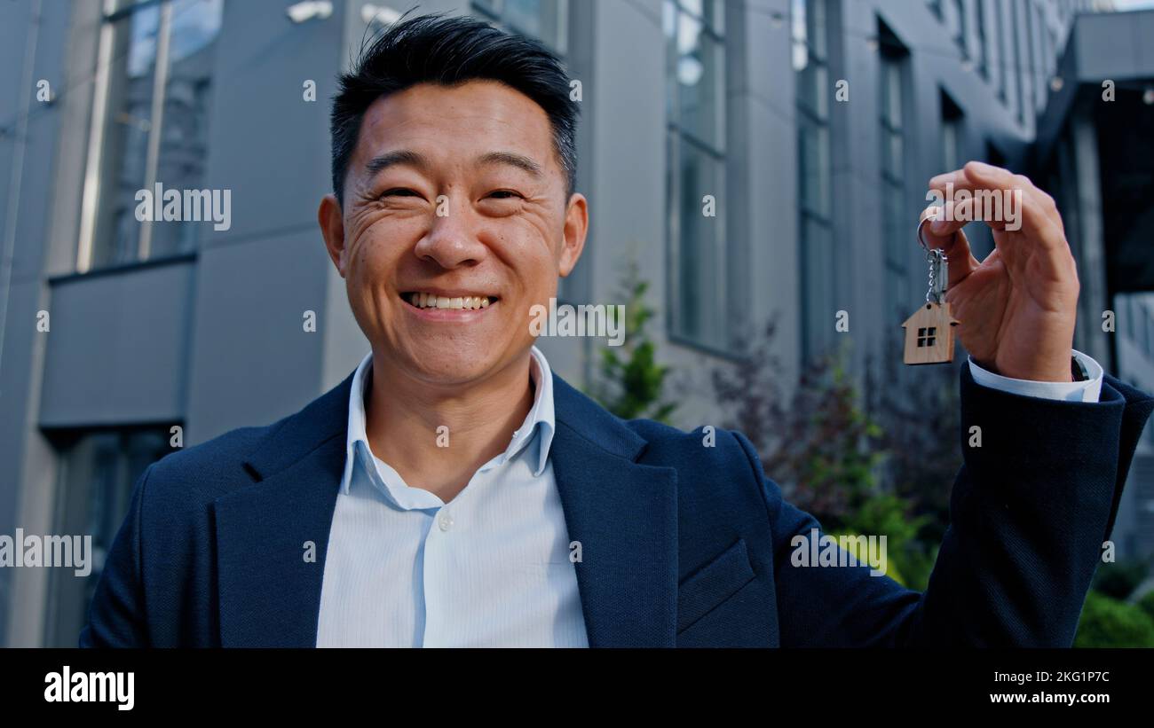Joyeux sourire asiatique adulte 40s homme tenant des clés portrait extérieur gagner réaction victoire célébrer homme immobilier agent investisseur acheteur vendre Banque D'Images