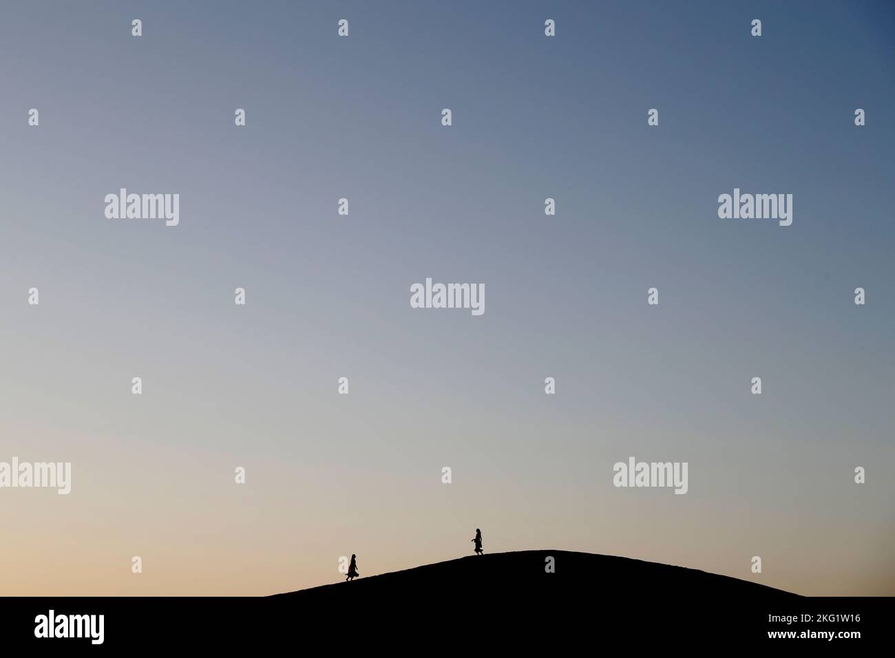 Deux silhouettes sur une dune de sable. Méditation au coucher du soleil dans le désert. Concept de religion, de foi, de prière et de spiritualité. Banque D'Images