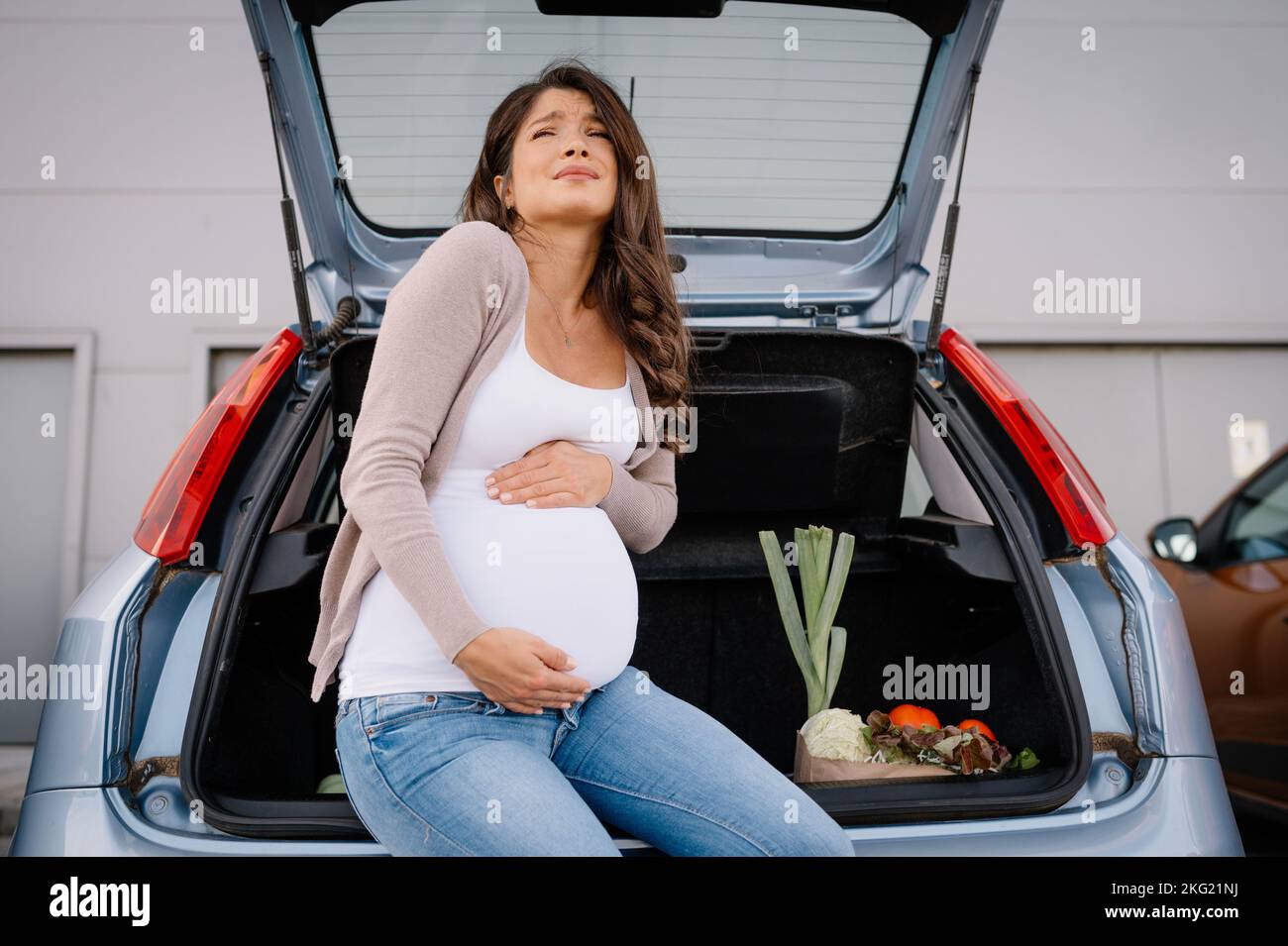 Future mère sensation de douleur dans l'abdomen ventre pendant les achats de maternité. Banque D'Images