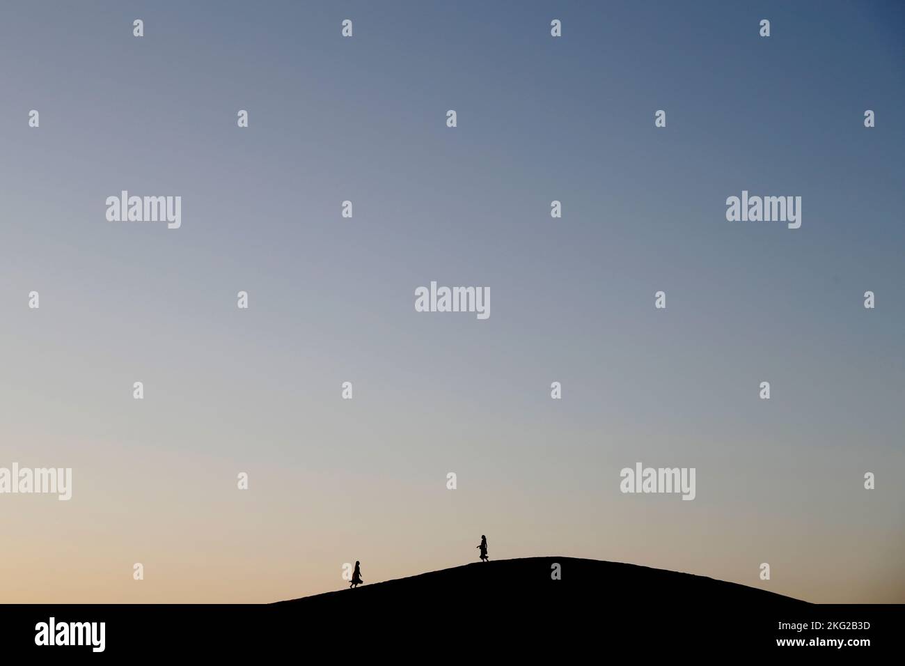 Deux silhouettes sur une dune de sable. Méditation au coucher du soleil dans le désert. Concept de religion, de foi, de prière et de spiritualité. Banque D'Images