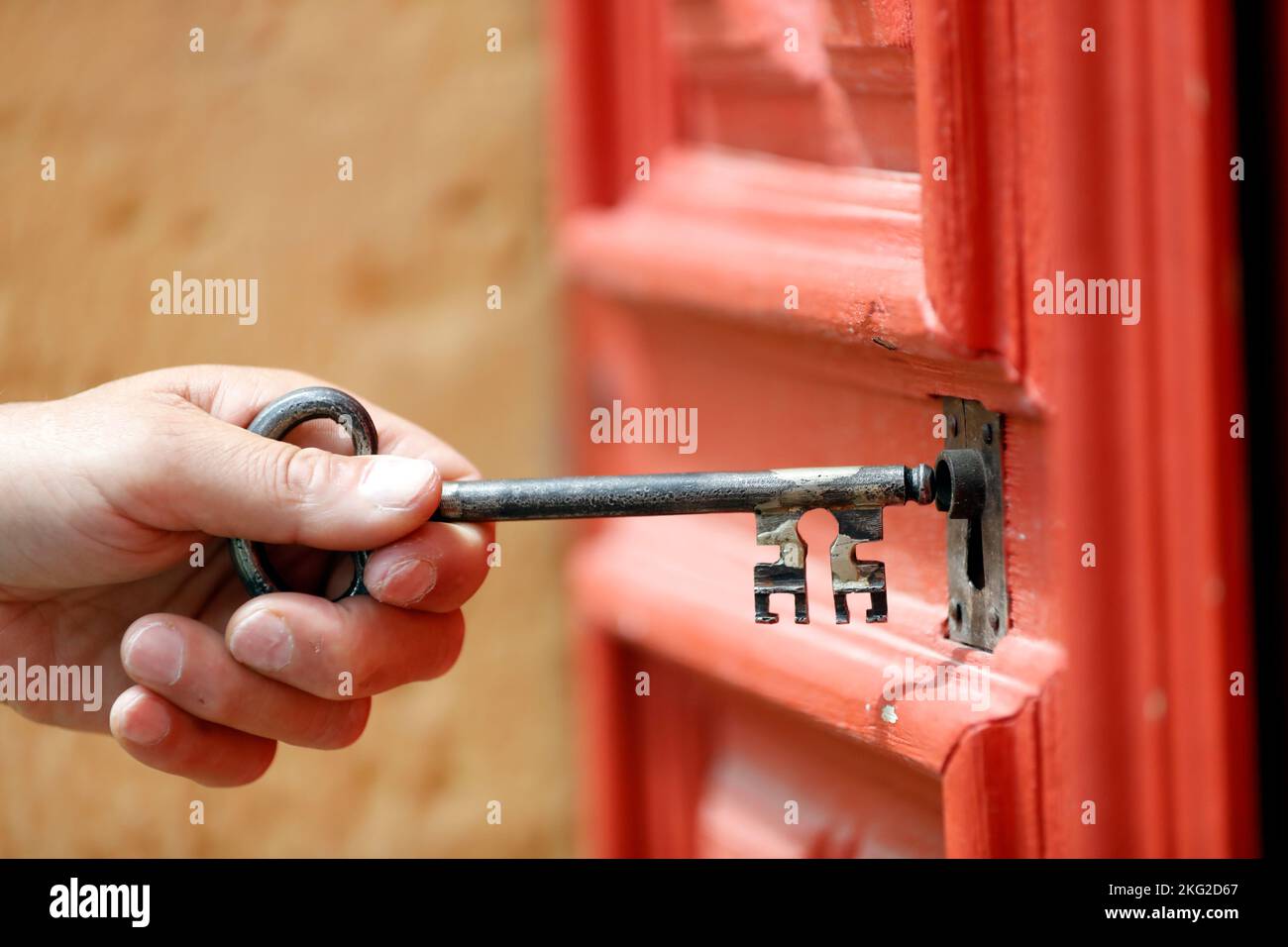 Main tenant une vieille clé rouillée pour la mettre dans la serrure d'une porte en bois. Banque D'Images