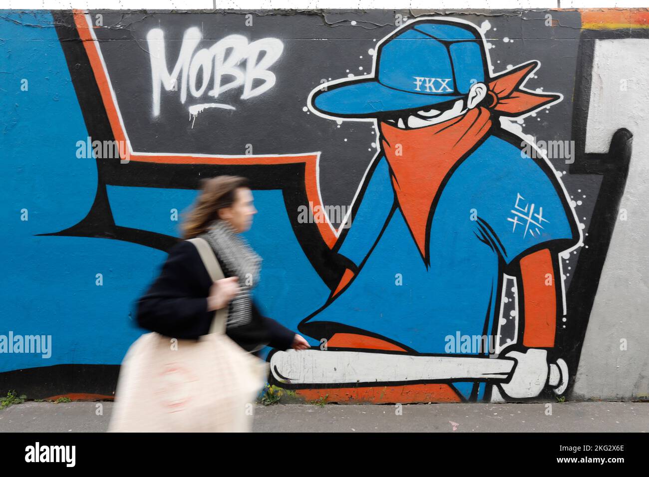 Femme marchant devant un mur avec l'art de rue à Paris, France Banque D'Images
